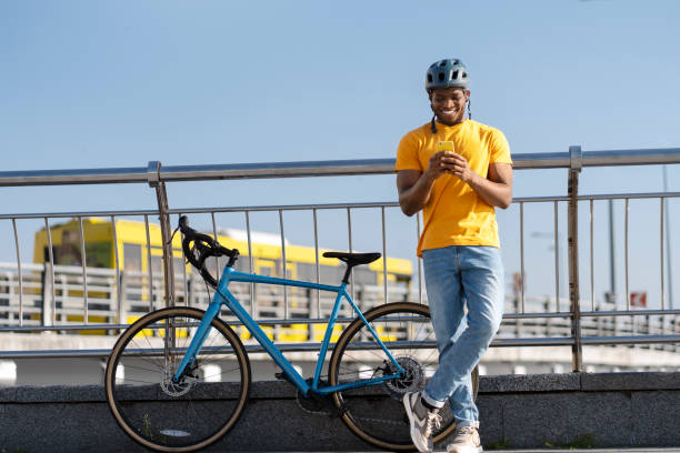 Smiling African American man in helmet holding mobile phone looking at screen