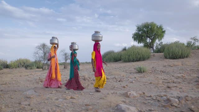 Indian young girls carrying water from well, desert village, India