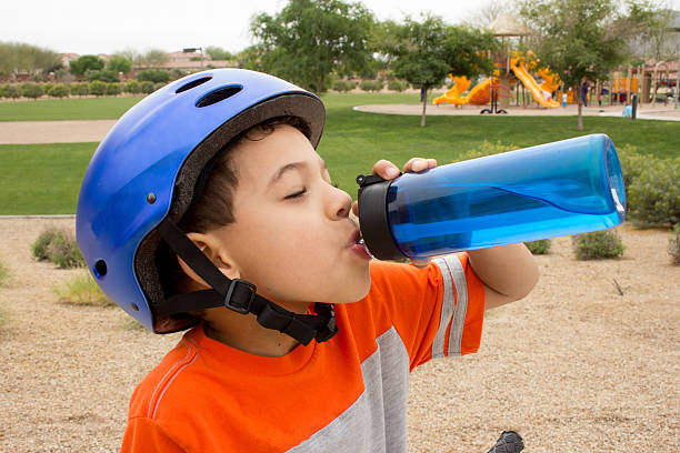 soif garçon de l'eau potable à l'extérieur - sports helmet photos et images de collection