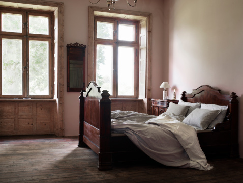 The pale morning sun shines through the window to the old decorated scandinavian bedroom. 