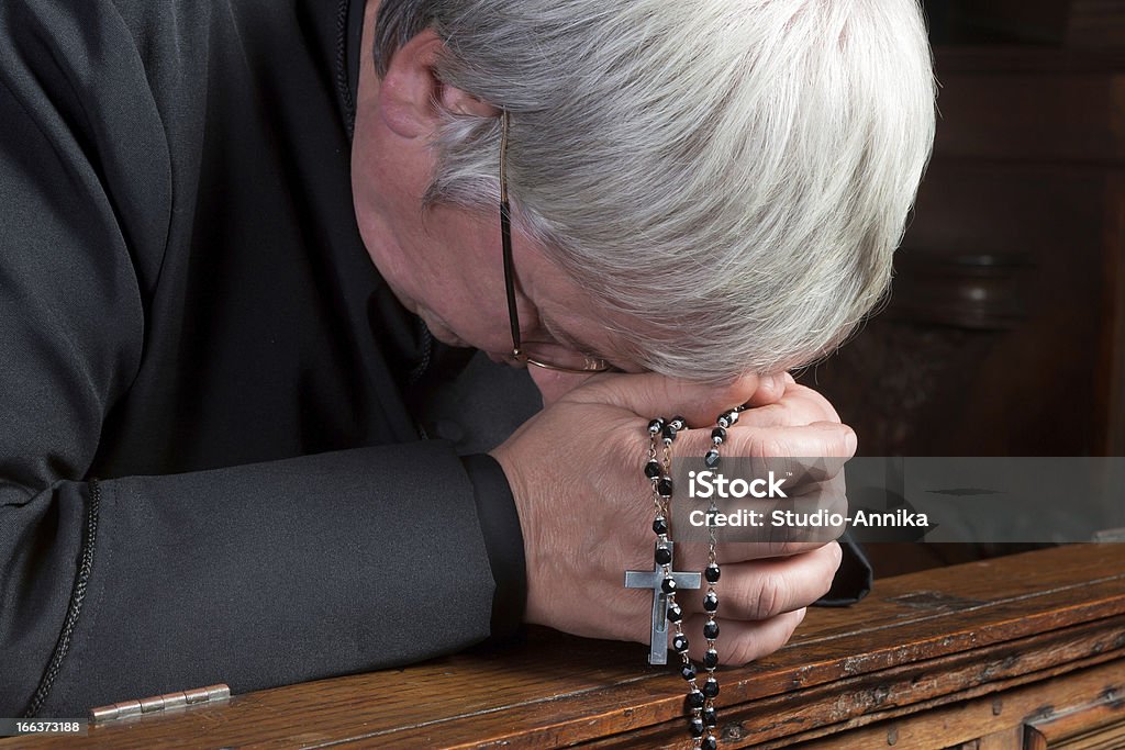 Humility Humble priest kneeling down and praying with his rosary Priest Stock Photo