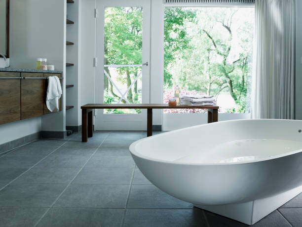 Free standing bathtub in corian Bathtub in tiled bathroom with windows towards garden wet wood texture stock pictures, royalty-free photos & images