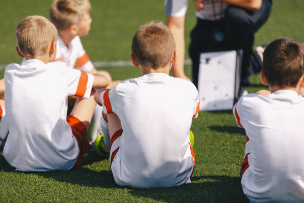 istock Children boys on football training with a coach. Trainer explaining tactics using strategy whiteboard. Boys listening to coach at soccer practice 1663743777