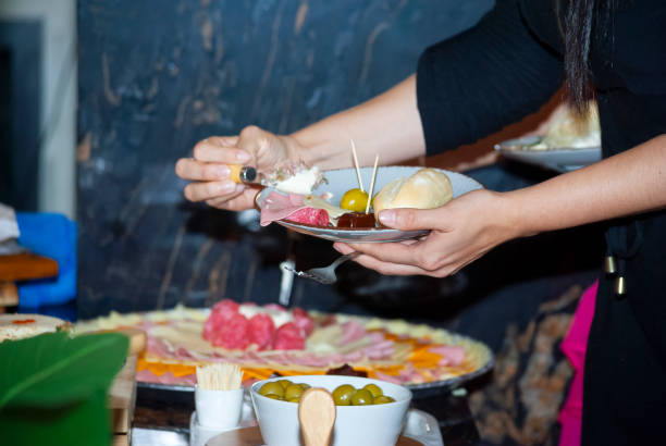 Antipasto buffet group of people helping themselves to individual plates, a celebration of flavor and color in elegant space.