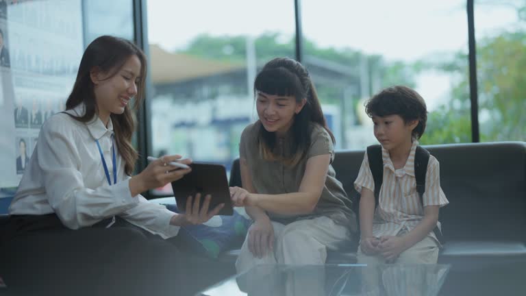 Mother and child chat with cheerful teacher using tablet to discuss tuition at international school