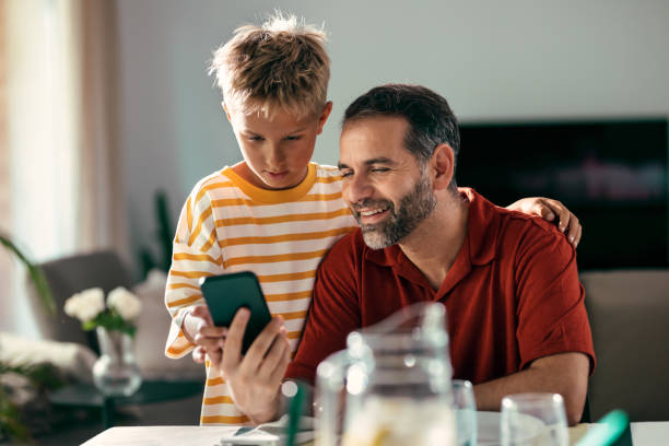 istock Handsome father and her cute son using smartphone before lunch in the kitchen at home 1663765387