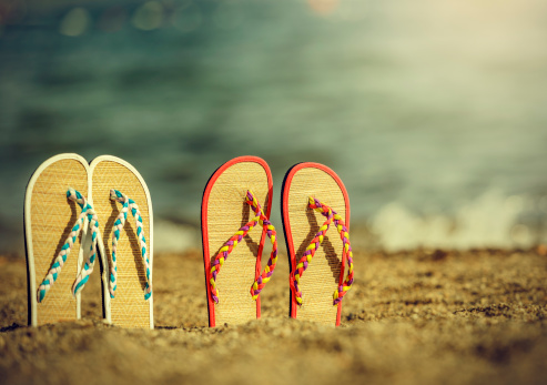 pair of colorful slippers in sand.