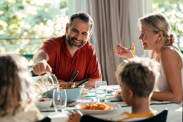 bella famiglia gentile che parla mentre mangiano insieme nella cucina a casa - 4 of a kind foto e immagini stock