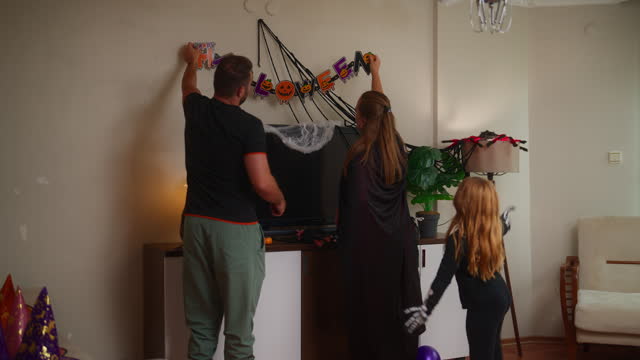 Young family decorating their home for family Halloween party