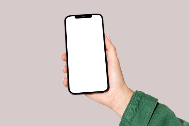 Female hand holding cell phone with blank screen on pink background. Mockup