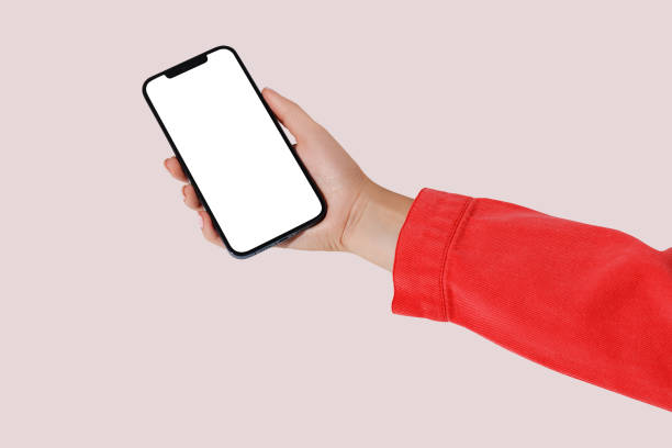 istock Female hand holding cell phone with blank screen on pink background. Mockup 1663785655