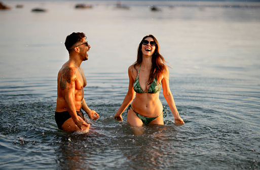 Beautiful young couple standing in water having fun and enjoying their summer vacation on the beach