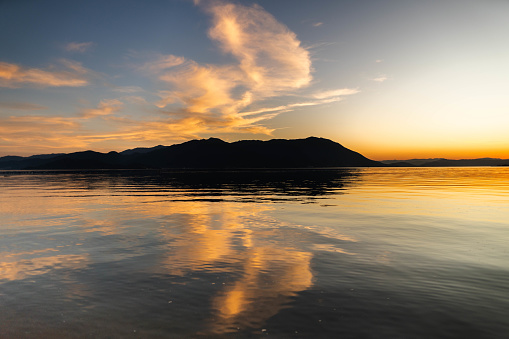 Calm beach with reflection of sky and mountain during sunset