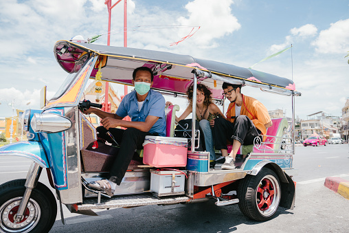 Cheerful friends enjoy memorable moments together in a Tuk Tuk Thailand.