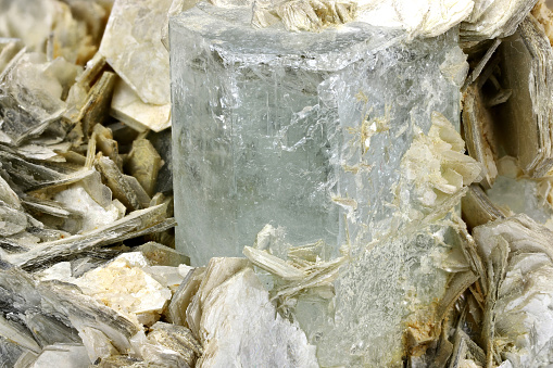 A crystal and stone cluster with clear white quartz, silver metallic pyrite and black tourmaline surrounded by matrix macro close up isolated on a white surface background