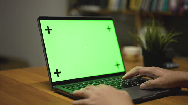 Laptop With Green Screen, Notebook Computer Standing On Wooden Table At Home, Night Working At Home