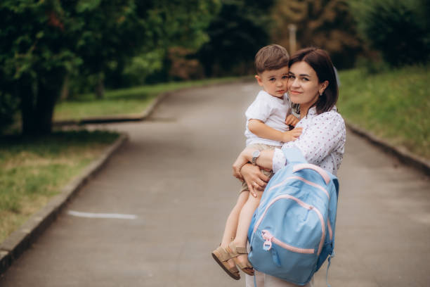 istock Child going back to school. Mother and kid getting ready for first school day after vacation. Little boy and mom going to kindergarten or preschool. Student packing books, apple and lunch in backpack. 1663820566