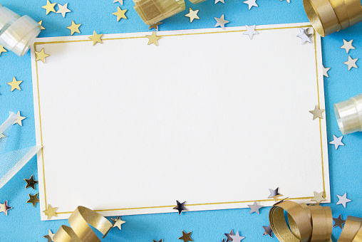 A blank card with gold and cream ribbons and stars on a light blue background, with copy space.  
Celebration background.