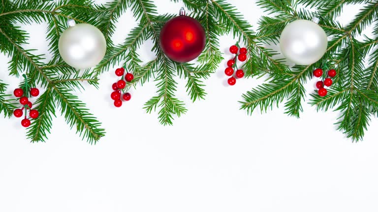 Natural green spruce branches decorated with red berries and Christmas holiday balls. White background.