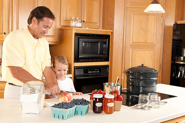 canning: pai e filho fazendo caseiros, compotas de frutas e vegetais cultivadas no local usando - jar canning food preserves - fotografias e filmes do acervo