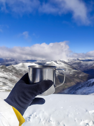 Hand holding a cup of tea with a snowy mountain landscape in the background