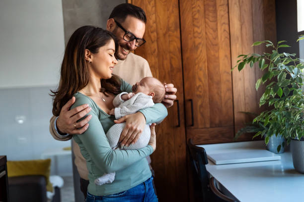 retrato de jovem homem feliz e mulher segurando recém-nascido bonito bebê vestido com roupas brancas unissex. - newborn - fotografias e filmes do acervo