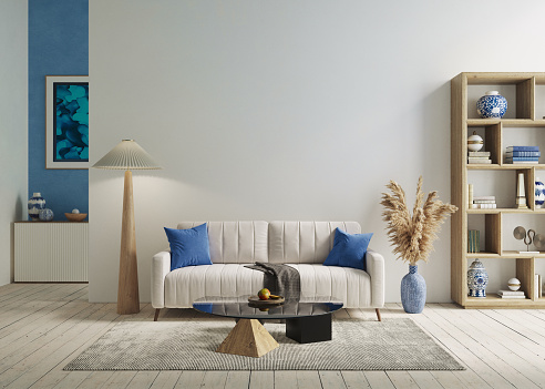 A stylish living room interior with brown and yellow coloured furniture and wooden elements with dark green coloured wall. Decorated with plants and butterfly specimen