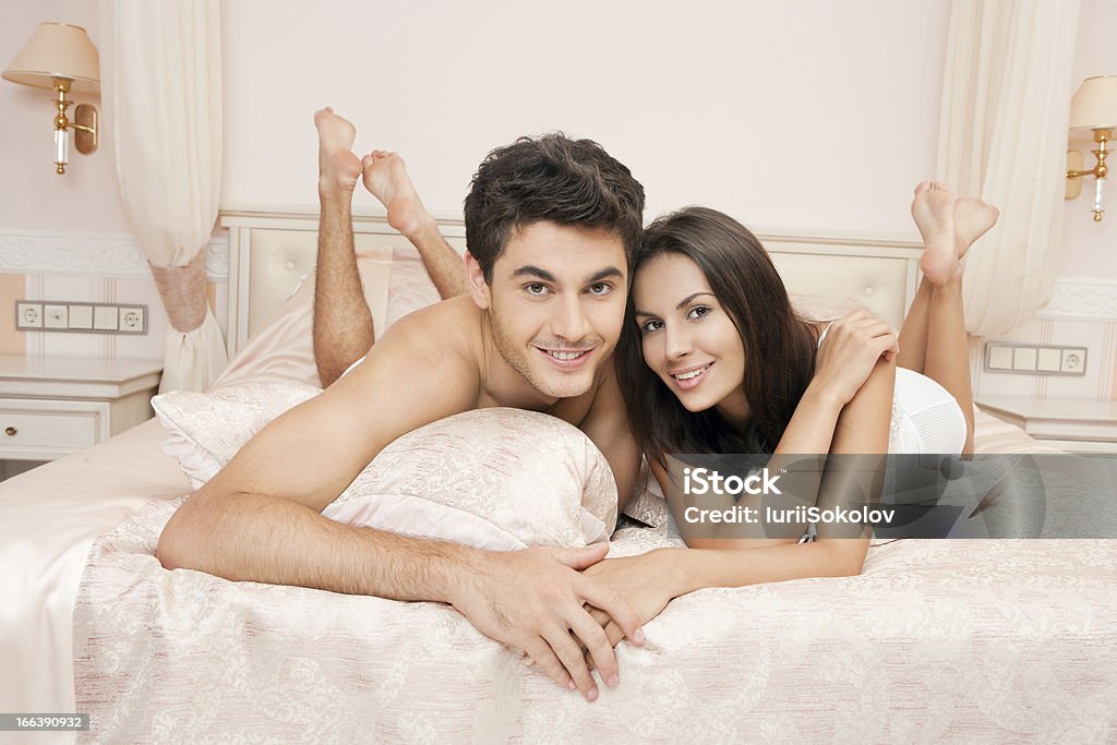 Young adult couple in bedroom Young adult heterosexual couple lying on bed in bedroom Adult Stock Photo