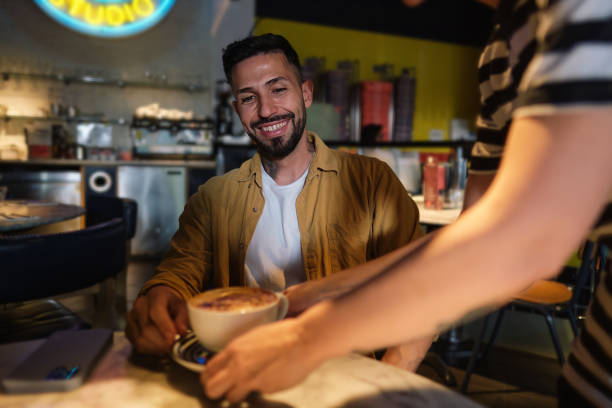 istock Young man receiving his coffee from a waitress 1663917909