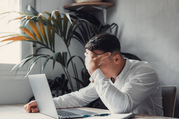 istock Stressed tired man in pain having strong terrible headache attack after computer laptop work, fatigued exhausted guy suffering from chronic migraine massaging temples to relieve head ache tension 1663930654
