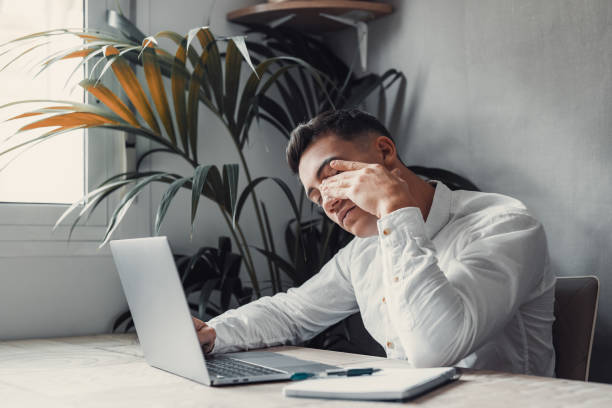 istock Stressed tired man in pain having strong terrible headache attack after computer laptop work, fatigued exhausted guy suffering from chronic migraine massaging temples to relieve head ache tension 1663935398