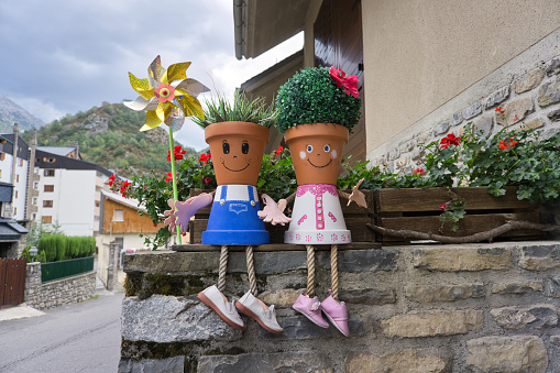 Painted pots that look like people, with plants imitating hair, decorating the entrance of a house.