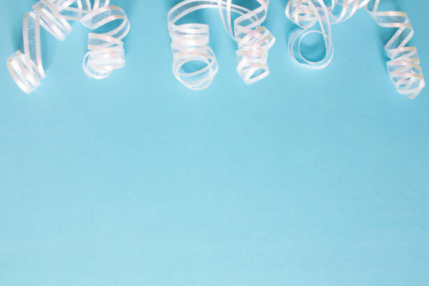 Curled white ribbons on a light blue background, with copy space.