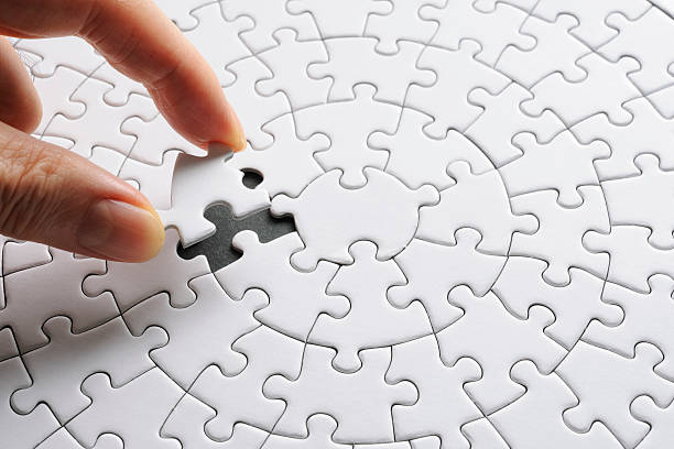 Holding a white blank final piece of the jigsaw Holding a red final piece of the jigsaw against black background. puzzle stock pictures, royalty-free photos & images