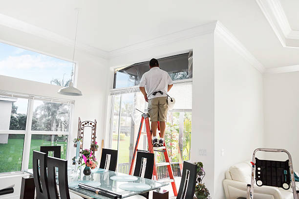 workman on ladder agregar tinting a la parte superior de la ventana interior - imagen virada fotografías e imágenes de stock