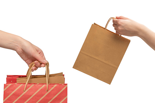 Paper bag in woman hands isolated on white background.