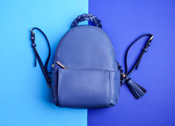 istock Modern royal blue leather backpack with zipped pocket with an original braided handle and a tassel isolated on a two-toned blue background. Creative design for advertising poster. Fashion blog. 1664022694