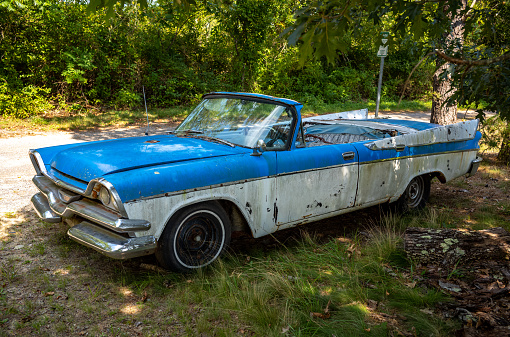 Views of a colorful, rusted and abandoned older car in the woods near the grass airstrip in Marstons Mills, on Cape Cod in MA.