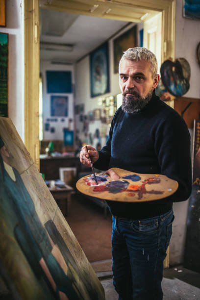 istock Mature man painting on canvas in art studio. 1664043935