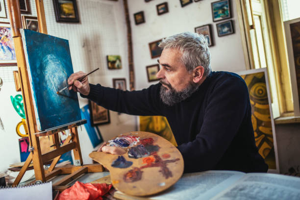 istock Mature man painting on canvas in art studio. 1664044522