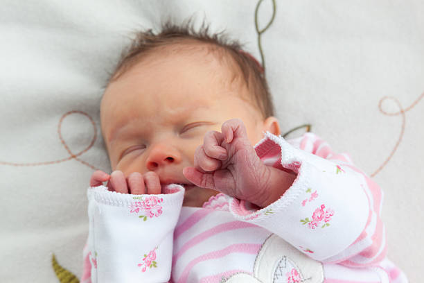 Newborn baby girl clutching her hands together Baby girl (6 days old) taken in a very soft light (a light tent) on a soft blanket. Focus is on her hands. day 6 stock pictures, royalty-free photos & images