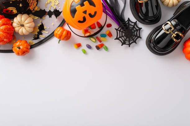 istock Alluring Halloween witch costume for little one. Top view shot of tiny boots, hat, magic wand, candy corn in basket, trick or treat treasures, pumpkins, cobweb, bats on white backdrop with text area 1664068076