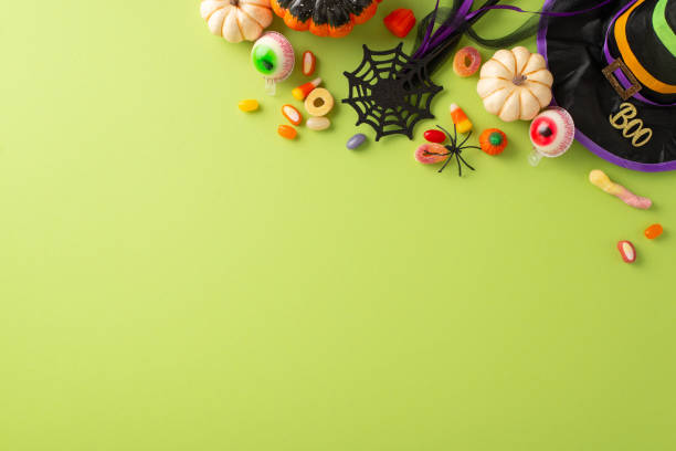 istock Captivating Halloween night event for youngsters idea. Top view snapshot showcasing confectioneries, child costume elements, and spooky decor on a green isolated setting, designed for adverts or text 1664068091