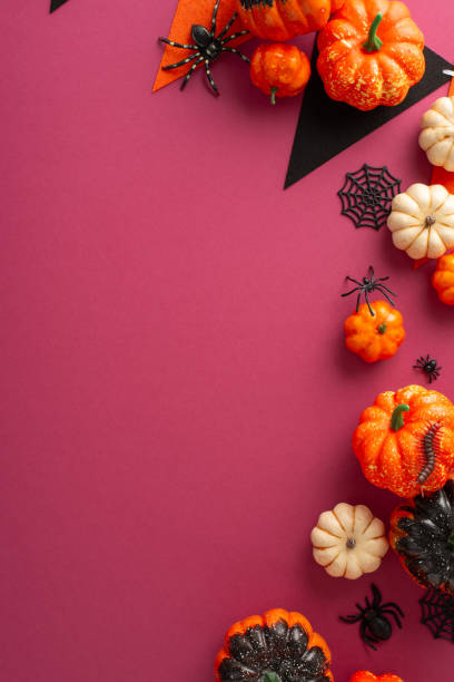istock Elevate the carnival excitement with this Halloween layout. Vertical top view shot featuring festive garland and party accessories amidst pumpkins, spiders, centipede and cobweb on a crimson canvas 1664068112