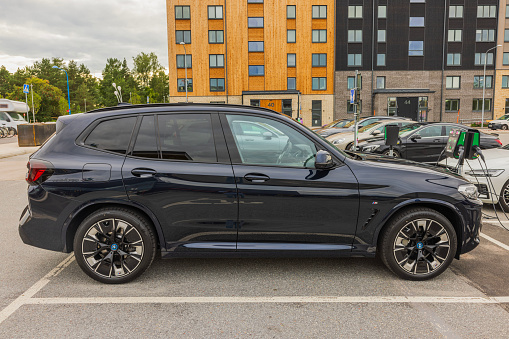 Sweden. Uppsala. 08.31.2023. Close-up view of electrical BMW iX3 M parked on parking lot equipped with charger.