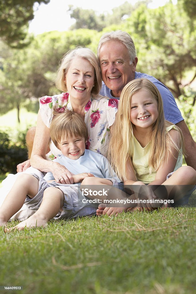 Avós e netos sentado no Parque juntos - Foto de stock de Avós e Avôs royalty-free