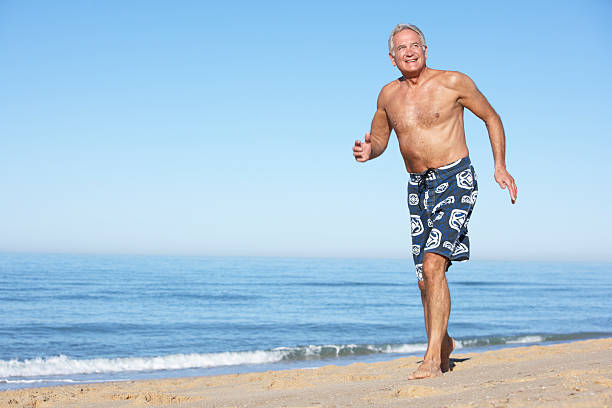 老人男性が夏のビーチに沿って - swimming trunks beach men swimwear ストックフォトと画像