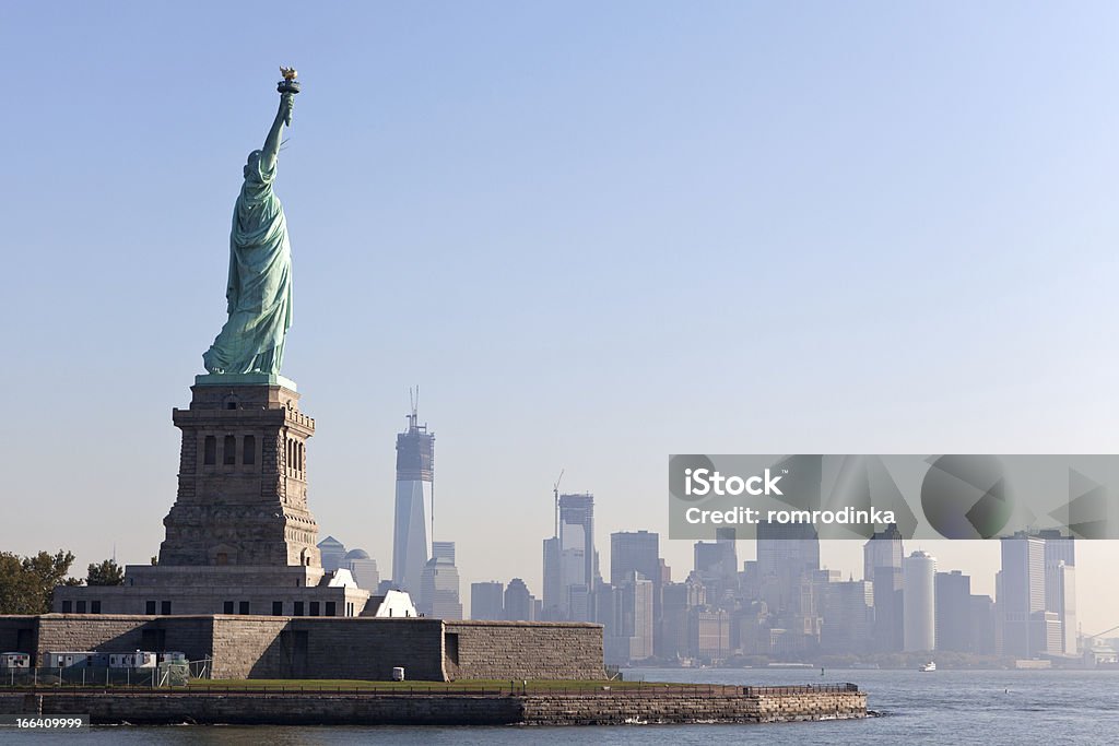The Statue of Liberty and New York City The Statue of Liberty free of tourists and New York City Downtown on sunny early morning Adult Stock Photo