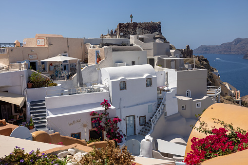 Oia, Santorini, Greece - July 3, 2021: Whitewashed buildings and the ruins of Castle of Agios Nikolaos on the edge of the caldera cliff, Oia village, Santorini, Greece