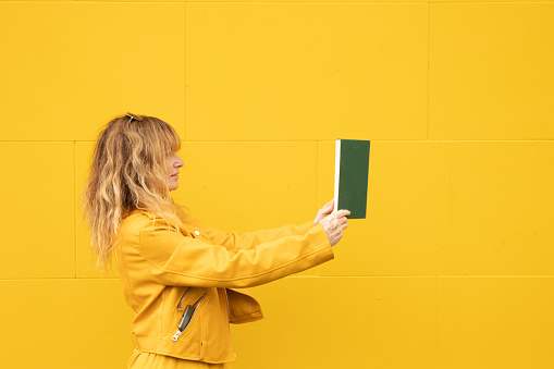 woman on yellow background with book, reading